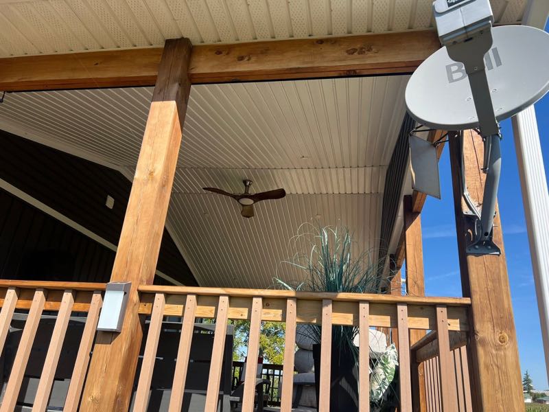 Covered porch with wood posts and railings, a white panelled ceiling and a ceiling fan