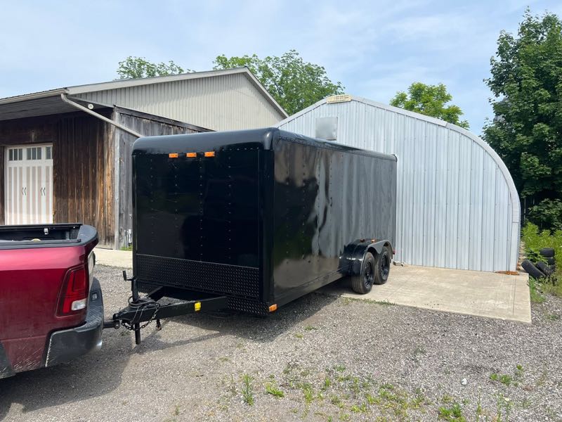 Black enclosed trailer hitched to a red pickup truck